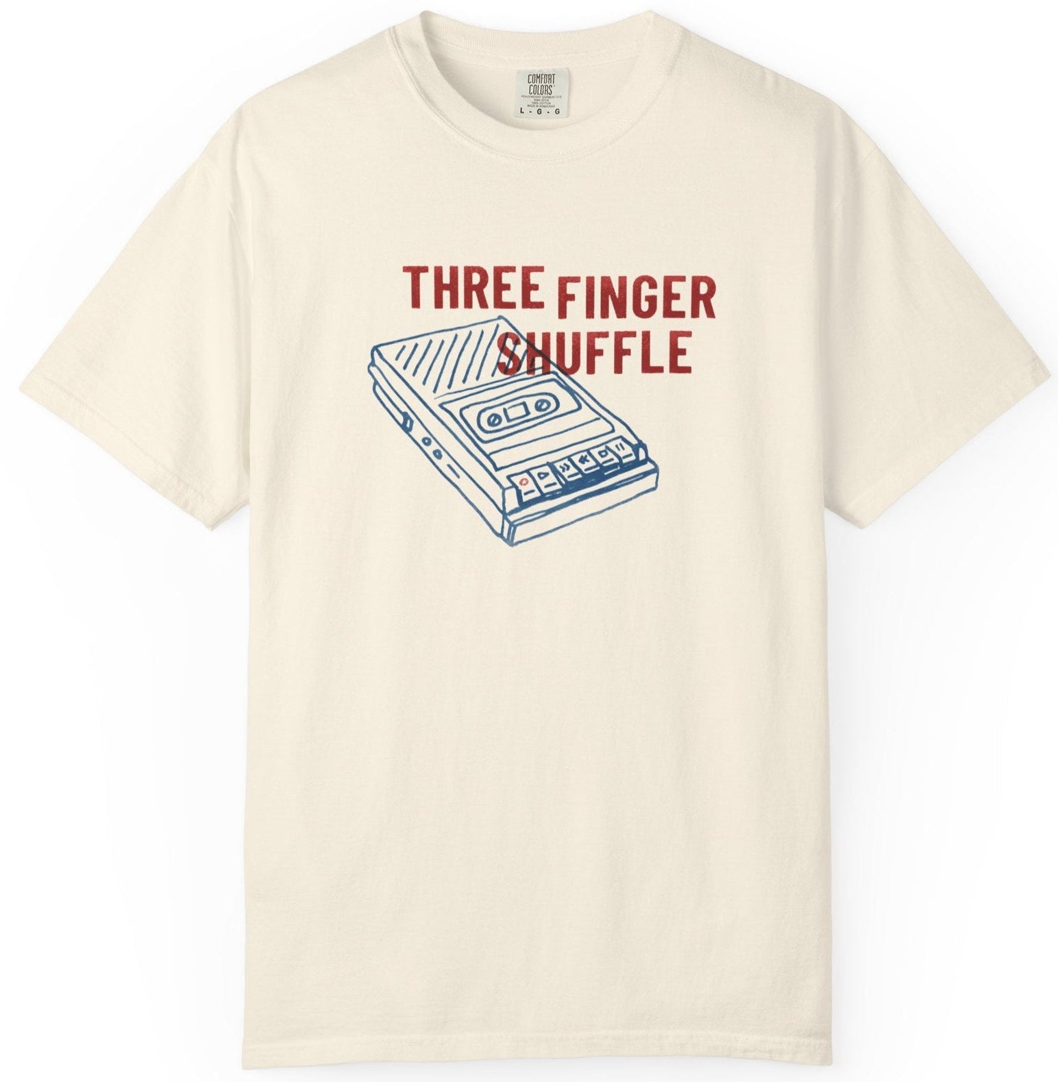 Beige t-shirt with a cassette tape graphic and 'Three Finger Shuffle' text on a white background