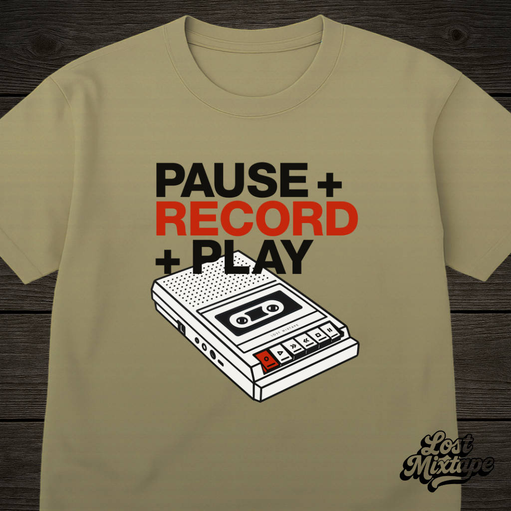 Khaki t-shirt with a cassette tape graphic and text on a wooden surface