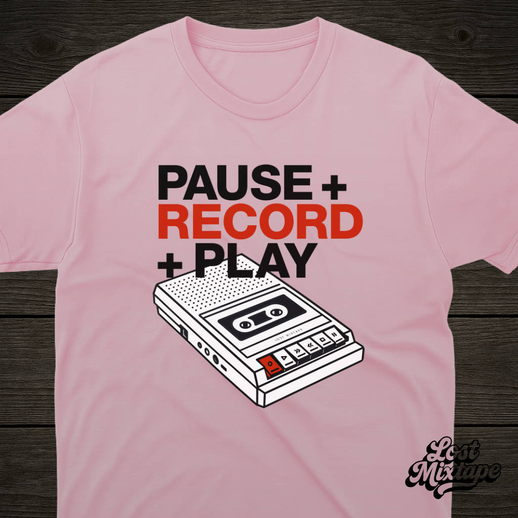 Pink t-shirt with a cassette tape graphic and text on a wooden surface